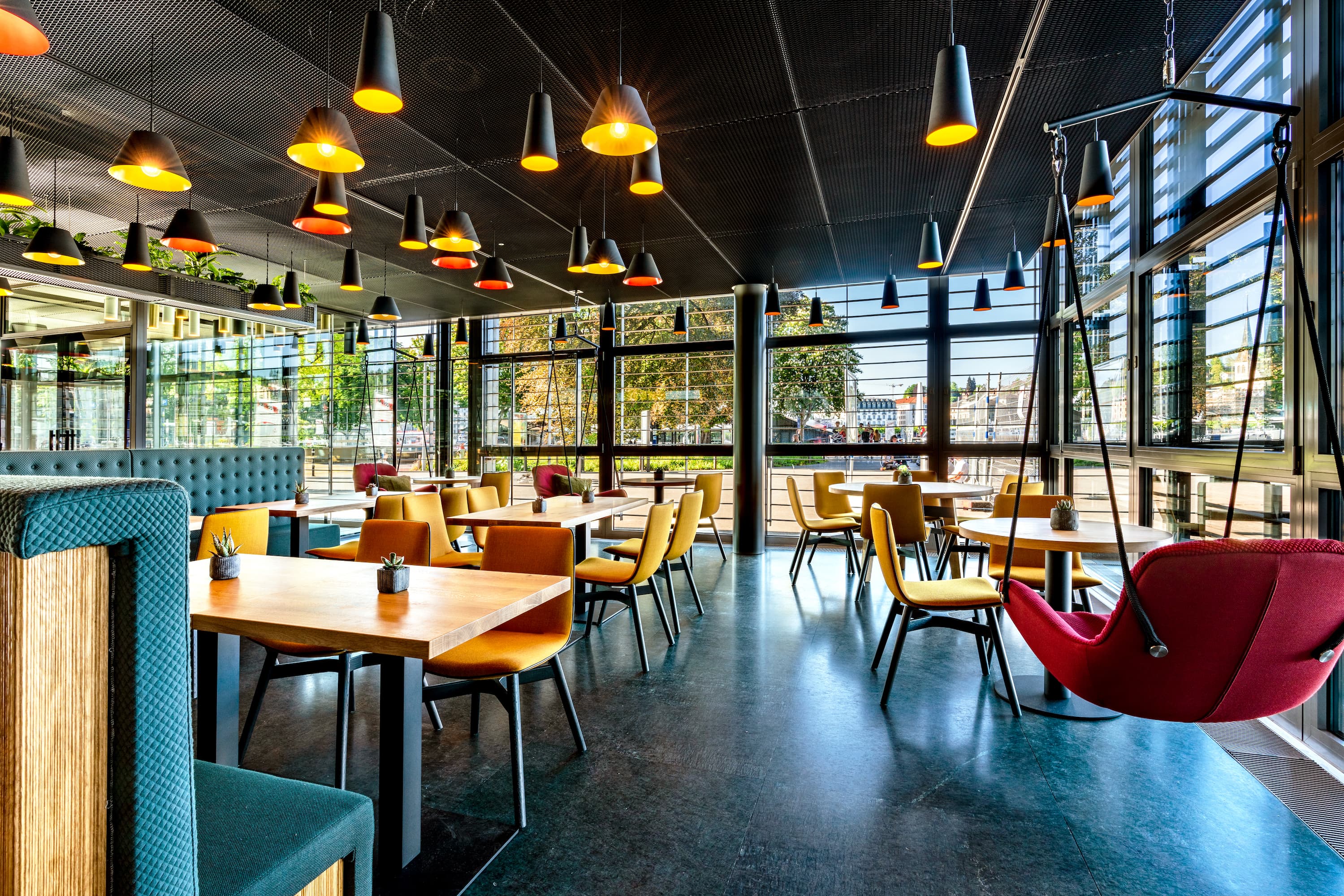 Tische und Hängesessel in der Deli Cafénbar Le Piaf im KKL Luzern mit Sicht auf den Europaplatz